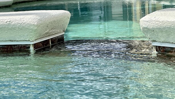 Ein klares Schwimmbecken mit zwei weißen, strukturierten Bänken an jeder Seite.