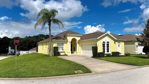 A residential house with a garage, a driveway, and a stop sign. - Charming Pool Home, with game room. 15 minutes from Disney parks. (Davenport)