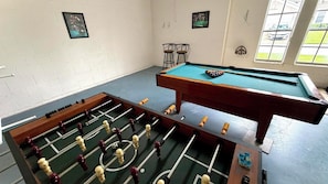 A room with a foosball table, a pool table, and two chairs. - Charming Pool Home, with game room. 15 minutes from Disney parks. (Davenport)