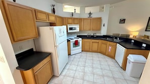 A kitchen with wooden cabinets, a white stove, a microwave, and a sink. - Charming Pool Home, with game room. 15 minutes from Disney parks. (Davenport)