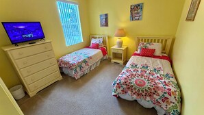 A bedroom with two single beds, a dresser, a television, and a window with blinds. - Charming Pool Home, with game room. 15 minutes from Disney parks. (Davenport)