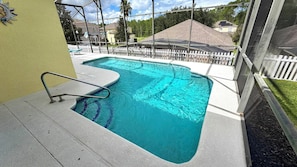 A swimming pool with a metal ladder, surrounded by a white fence, and a view of houses in the background. - Charming Pool Home, with game room. 15 minutes from Disney parks. (Davenport)