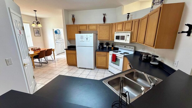 A kitchen with wooden cabinets, a refrigerator, a microwave, a stove, and a sink. - Charming Pool Home, with game room. 15 minutes from Disney parks. (Davenport)