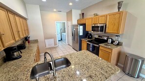 A kitchen with granite countertops, stainless steel appliances, wooden cabinets, and a stainless steel sink.