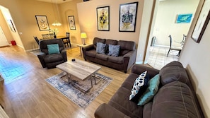 A living room with a sofa set, a coffee table, and a dining area with chairs and a table. - Envious Highlands Reserve pool home with recent upgrades. (Davenport)