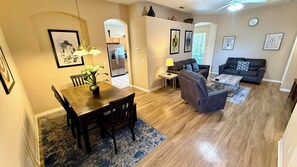 A living room with a sofa, a coffee table, and a dining area with a table and chairs.