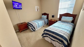 A bedroom with two beds, a TV mounted on the wall, a nightstand, and a window with blinds. - Envious Highlands Reserve pool home with recent upgrades. (Davenport)