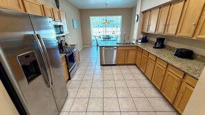 A kitchen with wooden cabinets, a stainless steel refrigerator, a dishwasher, and a granite countertop.