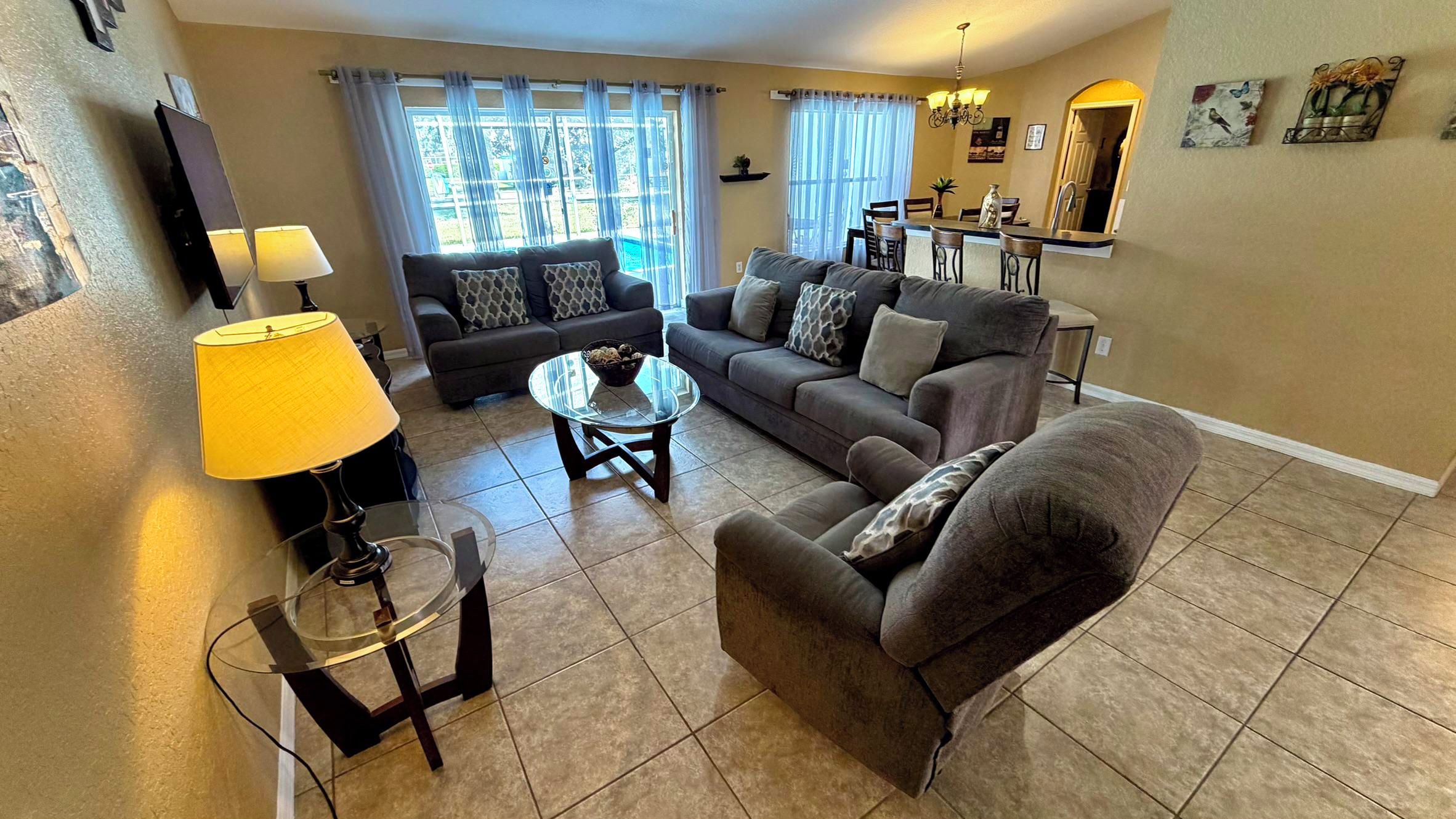 A living room with two sofas, a coffee table, a TV, and a dining area with chairs and a table.