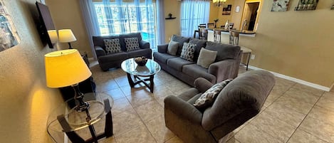 A living room with two sofas, a coffee table, a TV, and a dining area with chairs and a table.
