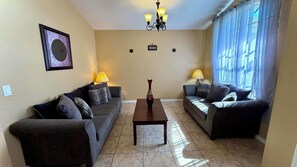 A living room with two sofas, a coffee table, and a chandelier.