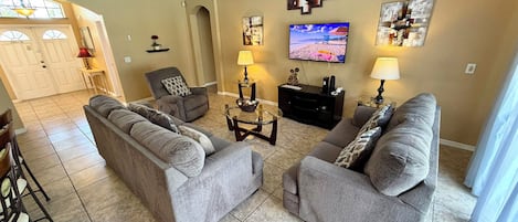 A living room with two grey sofas, a television, wall art, and a dining area with a table and chairs.
