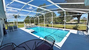 A covered outdoor swimming pool with lounge chairs and a table. - Stunning, large Highlands Reserve with game room and pool! (Davenport)