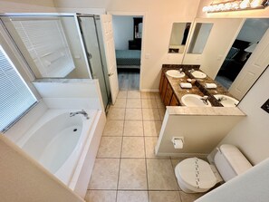 A modern bathroom with a walk-in shower, a bathtub, a double sink vanity, and a toilet. - Family time, quiet relaxation, Florida fun. Pool Home at Orange Tree (Clermont)