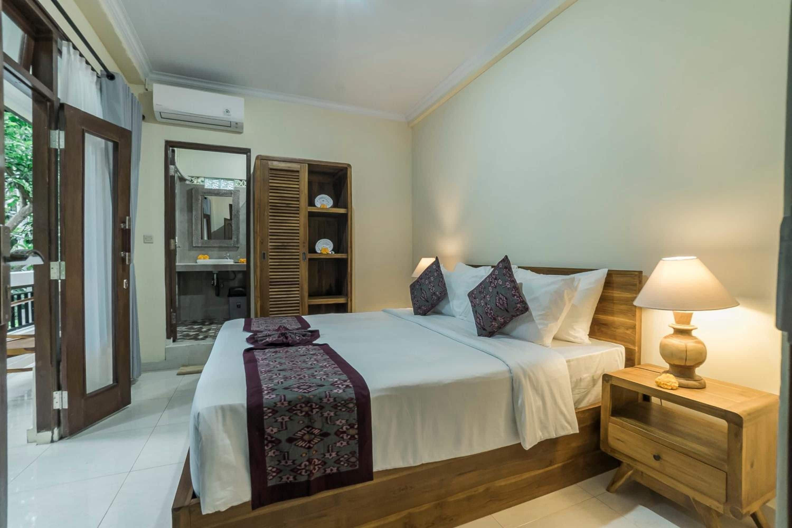 A bedroom with a bed, bedside table, lamp, and a wardrobe with a mirror.