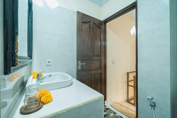 Un baño con un lavabo blanco, un espejo y una puerta de madera.