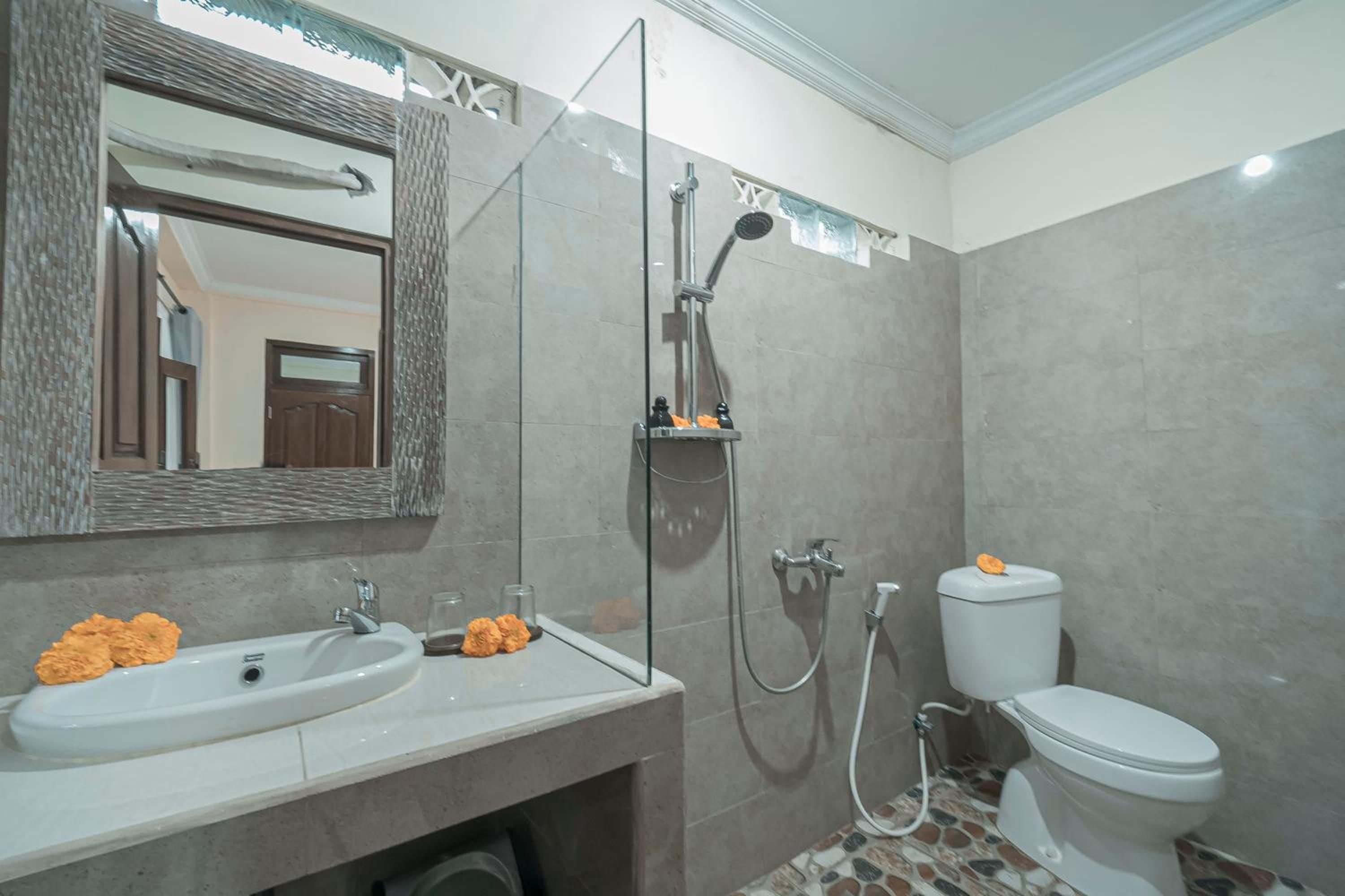 A bathroom with a sink, mirror, shower, and toilet.