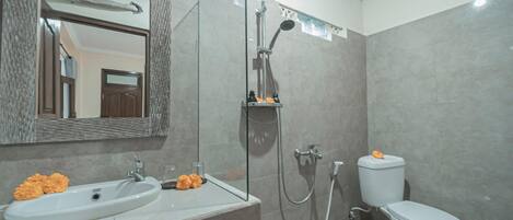 A bathroom with a sink, mirror, shower, and toilet.