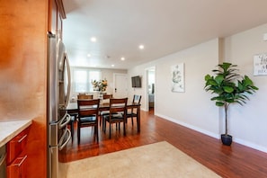 A modern kitchen with stainless steel appliances, a dining area with wooden chairs, and a potted plant. -  Marbella Lane Triplex San Jose 11‑Min to Levi’s (San Jose)