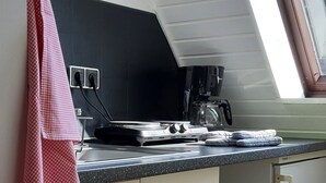 Une cuisine avec un plan de travail noir, une machine à café et une décoration en forme de cœur rouge.