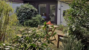 A garden with a wooden table and chairs, surrounded by various plants and trees. - Atelier 2 - Atelierhaus Tannenweg (Worpswede)