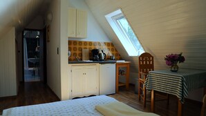 A compact room with a bed, a small kitchenette, a dining table with chairs, and a skylight. - Atelier 2 - Atelierhaus Tannenweg (Worpswede)