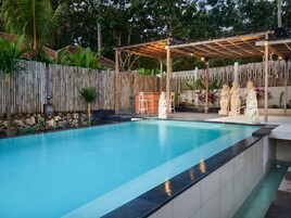 Una piscina al aire libre, sombrillas, sillones reclinables de piscina