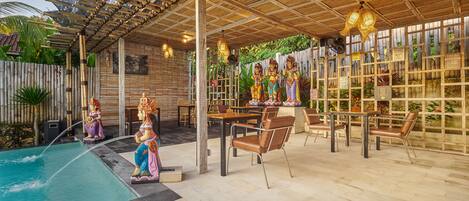 Un espacio al aire libre cubierto con piscina, asientos y estatuas decorativas.
