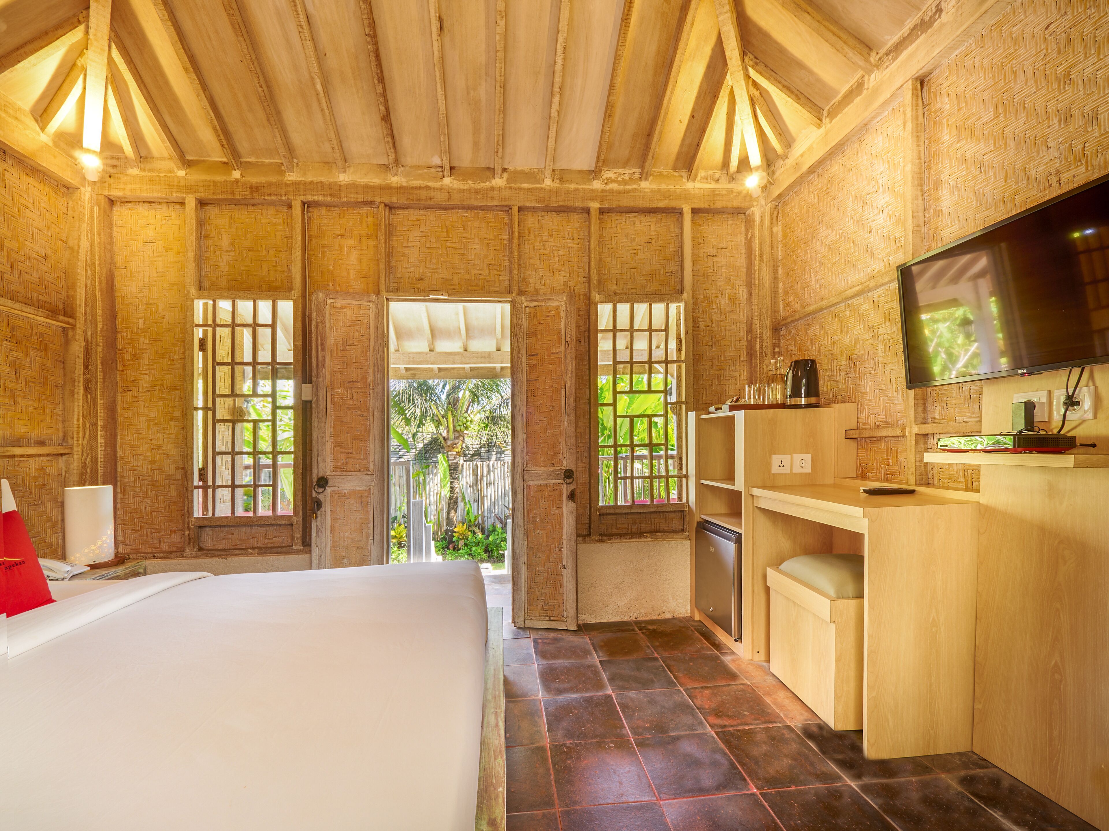 Une chambre avec un lit, un bureau, une télévision et une vue sur la verdure environnante.