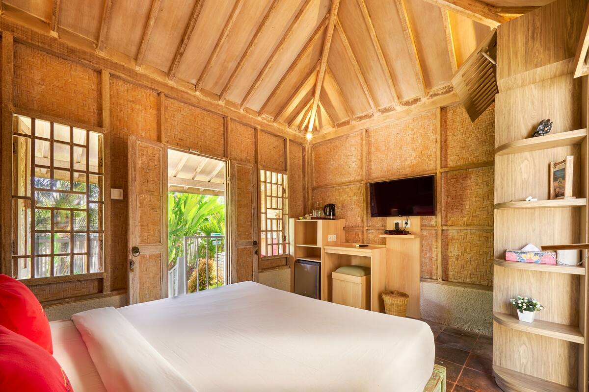 Ein Zimmer mit einem Bett, einem Fernseher, einem Schreibtisch und einem Regal.