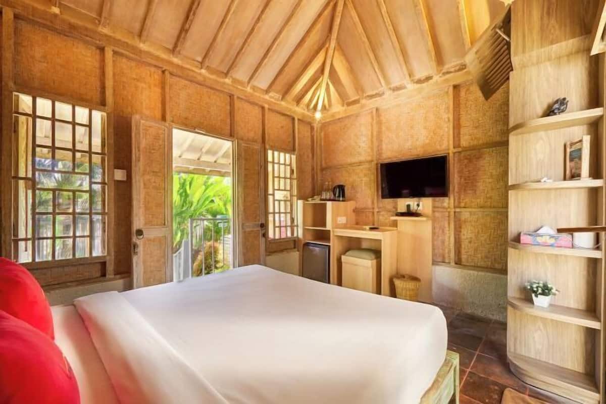 Ein Zimmer mit einem Bett, einem Fernseher, einem Schreibtisch und einem Regal mit Gegenständen.