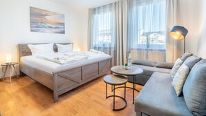 Ein modernes Hotelzimmer mit einem hölzernen Bett, einer Couch, einem kleinen runden Tisch und einem Bild an der Wand.