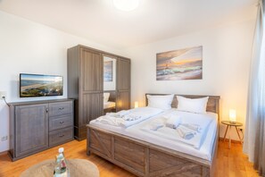 Una habitación de hotel con una cama de madera, un armario, un televisor y un cuadro en la pared.