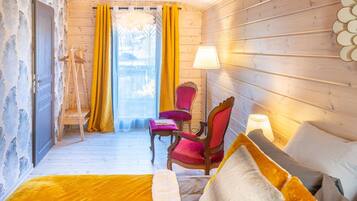 Une pièce chaleureuse aux murs en bois, avec un lit recouvert d’une couverture jaune, deux chaises et une lampe.