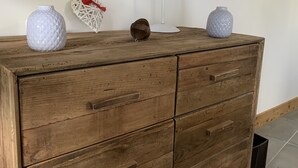 Eine hölzerne Kommode mit vier Schubladen, eine weiße Lampe und zwei dekorative Vasen darauf.