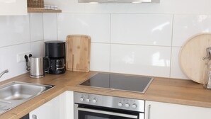 A modern kitchen with a stainless steel range hood, a built-in oven, a coffee maker, and a wooden cutting board. - Modern vacation apartment in a lovingly restored Lorraine farmhouse (Beckingen)