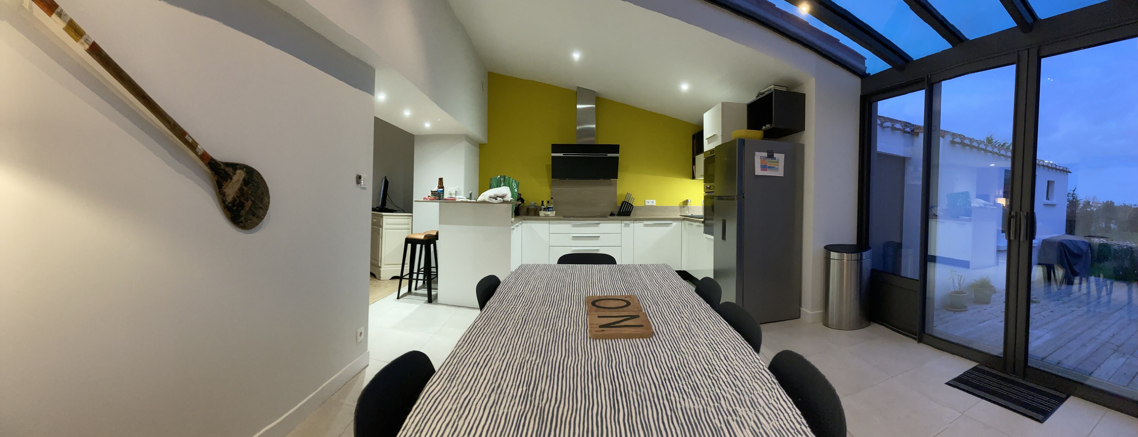 Una cocina moderna con una pared de acento amarilla, una campana extractora de acero inoxidable y un horno empotrado.