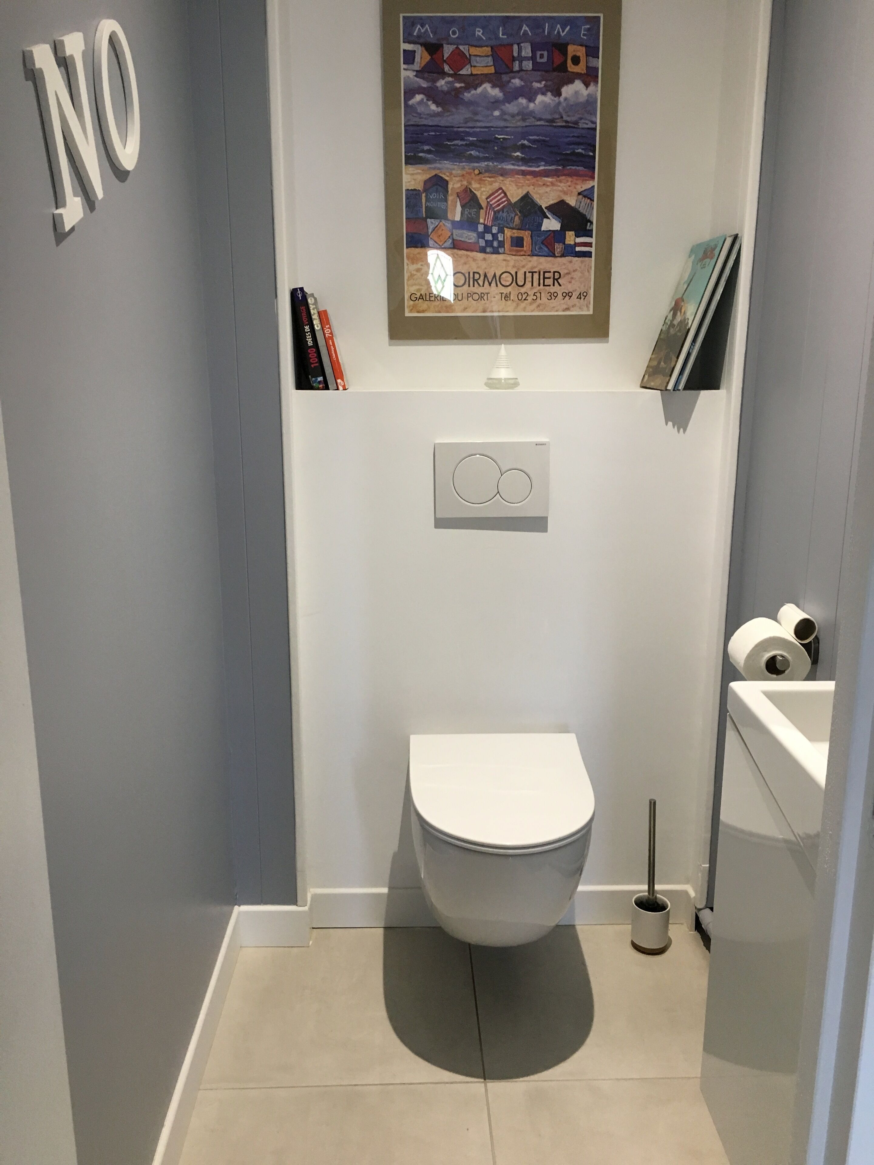 A compact bathroom with a white toilet, a small sink, and a toilet paper holder.