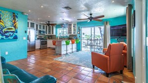 Un espacio habitable amplio con cocina, un comedor con sillas coloridas y un ventanal que ofrece vistas al exterior.