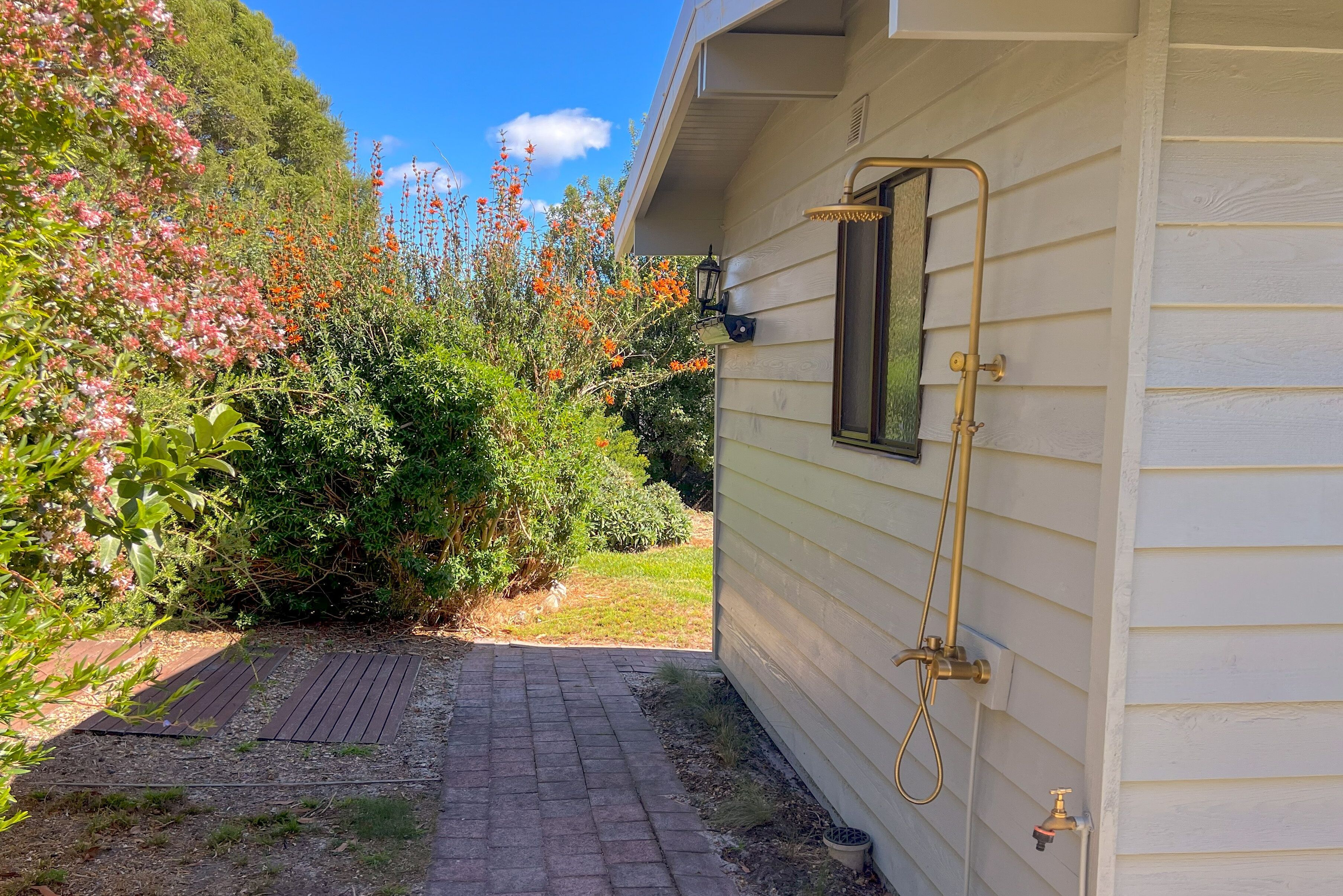 A pathway leading to a house with a built-in shower system.
