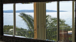 Ein Fenster mit Blick auf ein Gewässer und Palmen.