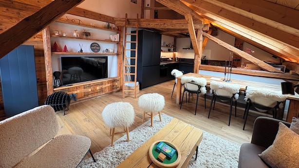 An attic room with a wooden ceiling, a fireplace, a TV, a dining table with chairs, and a ladder. - Very nice Apartment - Mont-Blanc view - 3 bedrooms (Saint-Gervais-les-Bains)