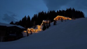 A snow-covered mountain with a lit chalet and a wooden cabin. - Very nice Apartment - Mont-Blanc view - 3 bedrooms (Saint-Gervais-les-Bains)