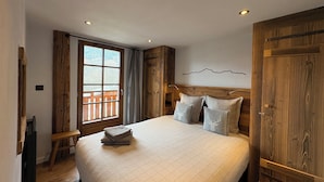 A bedroom with a large bed, wooden headboard, and a view through a window. - Very nice Apartment - Mont-Blanc view - 3 bedrooms (Saint-Gervais-les-Bains)
