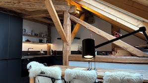 A modern kitchen with wooden beams, a dining area with chairs, and a pendant light. - Very nice Apartment - Mont-Blanc view - 3 bedrooms (Saint-Gervais-les-Bains)