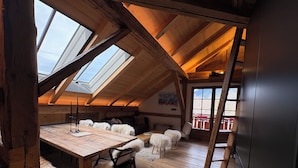 A high-ceilinged room with wooden beams, a skylight, a wooden table, and a sofa. - Very nice Apartment - Mont-Blanc view - 3 bedrooms (Saint-Gervais-les-Bains)