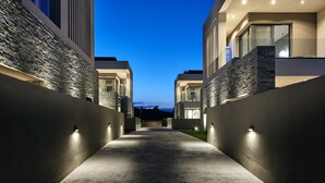 Un bâtiment moderne avec une façade en pierre et un chemin en béton menant à l’entrée.