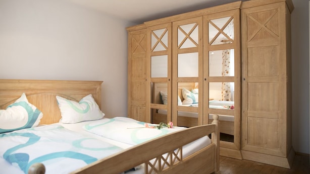 Une chambre à coucher avec un lit en bois, une armoire en bois dotée de portes en verre et une table de chevet.