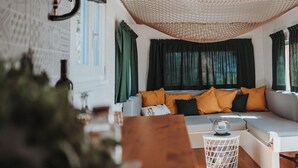 Un salon moderne avec un canapé blanc, des rideaux verts et un luminaire suspendu au plafond, fait de matériaux tressés.