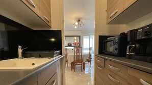 A modern kitchen with a central island, stainless steel appliances, and wooden cabinetry. - Spacious apartment for 4, balcony, sea view, near beach, parking, cleaning included (Saint-Hilaire-de-Riez)